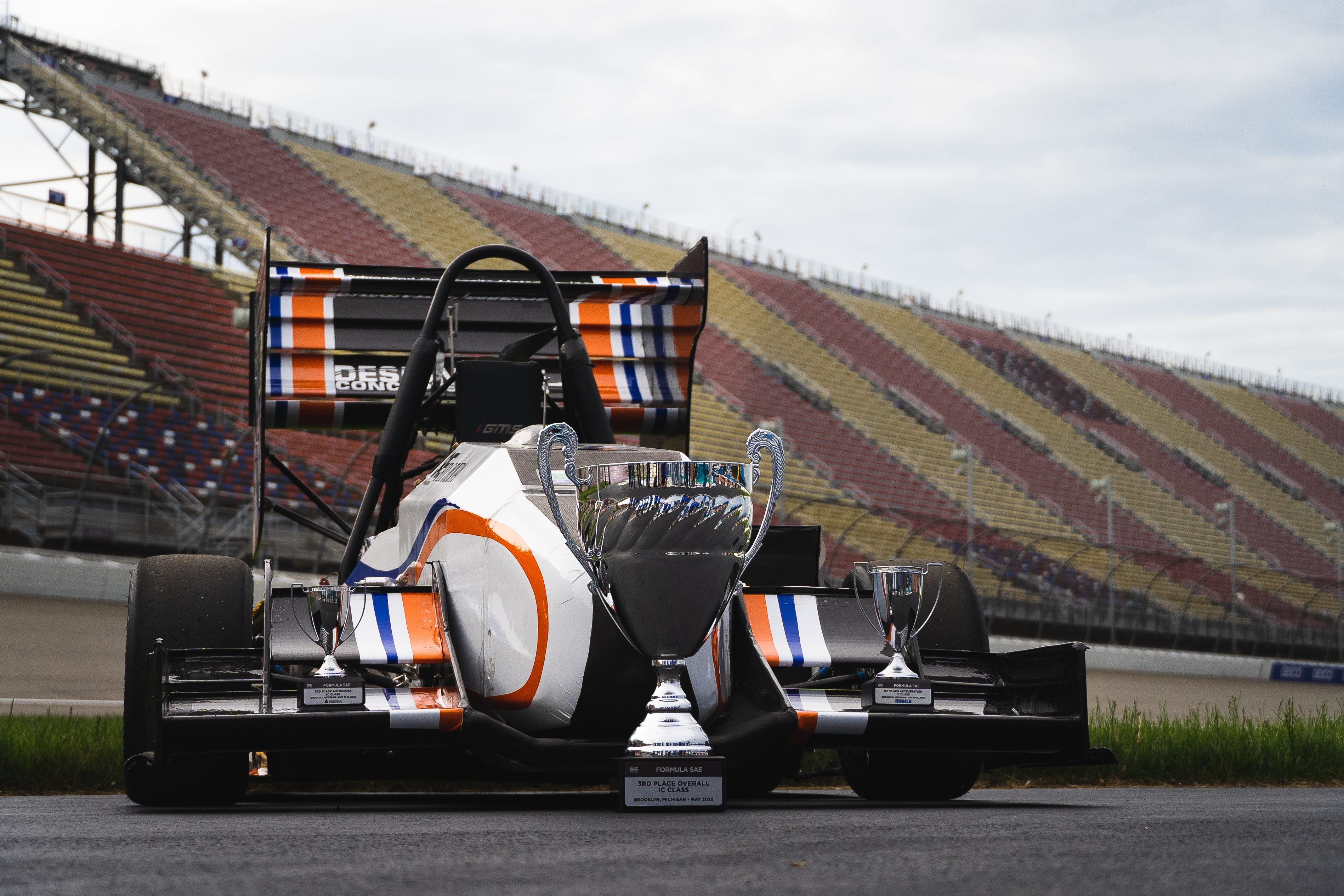 Image of a previous year's internal combustion engine taking a photo on the track with the 3rd place overall trophy